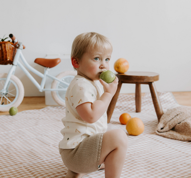 Picture of little boy wearing organic cotton knit shorts with faux drawstring in sandcastle color. 