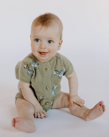 Baby wearing zebra print knit playsuit in sage