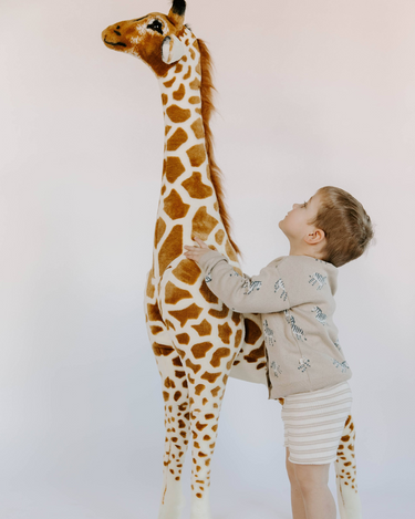 Little boy wearing organic cotton knit cardigan in mushroom beige with jacquard zebra pattern and magnetic button closures.