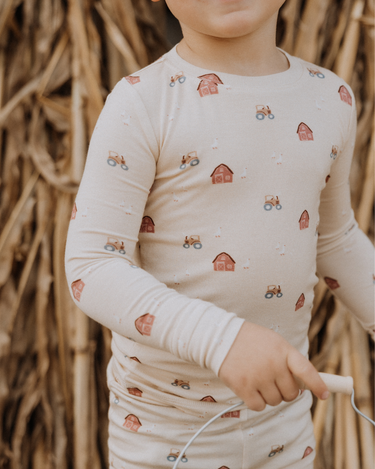 child wearing modal pajama set in light beige color with farm print