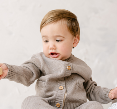 image shows baby boy wearing merino wool baby cardigan in heather brown