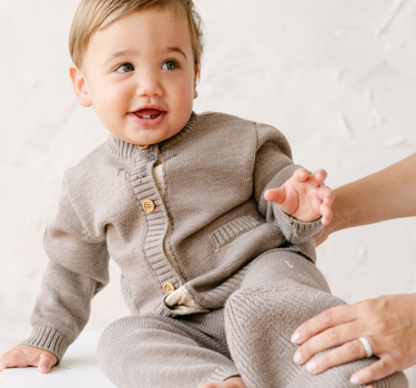 image shows baby boy wearing merino wool baby cardigan in heather brown