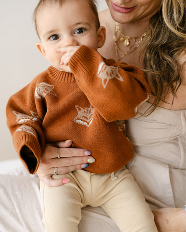 Image shows baby boy wearing organic cotton knit sweater with fox jacquard pattern in mocha. 