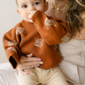 Image shows baby boy wearing organic cotton knit sweater with fox jacquard pattern in mocha. 