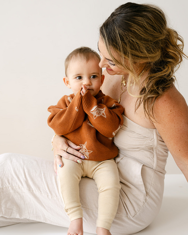 Image shows baby boy wearing organic cotton knit sweater with fox jacquard pattern in mocha. 