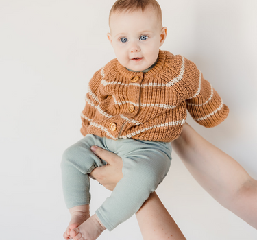 Picture shows baby girl in mom's arms wearing organic cotton knit cardigan with acorn and cream stripes and Magnetic Buttons. 