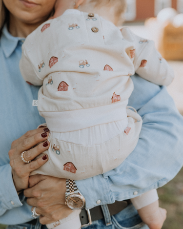 baby wearing organic cotton fleece sweatshirt in beige color with farm print and magnetic closures at the back of the neck