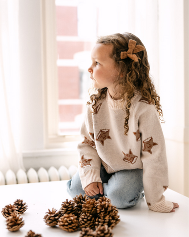 Image shows little girl wearing organic cotton knit sweater with jacquard fox pattern in pale pink. 